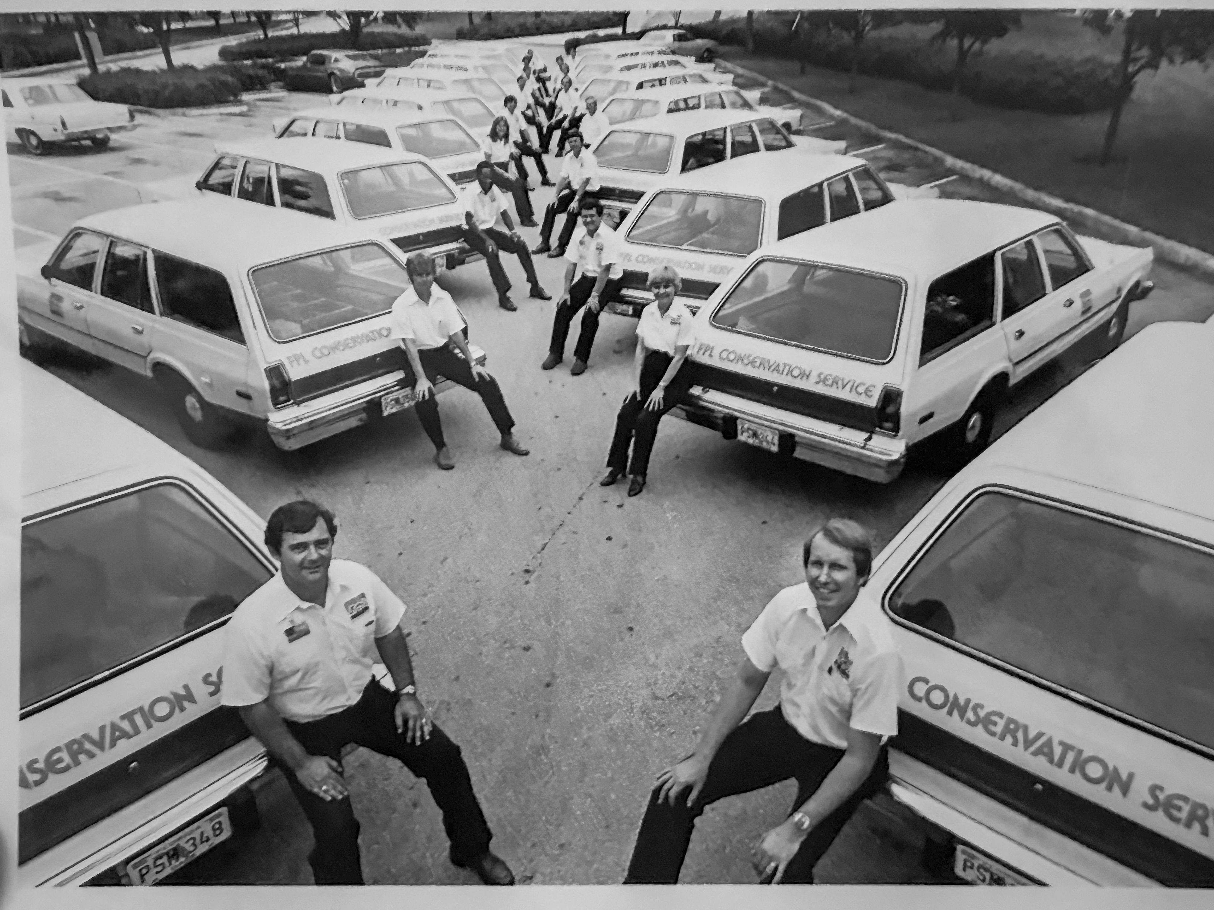 FPL energy auditors in the 1980s sit on the back bumpers of FPL station wagons that were labeled with FPL Conservation Service on the back